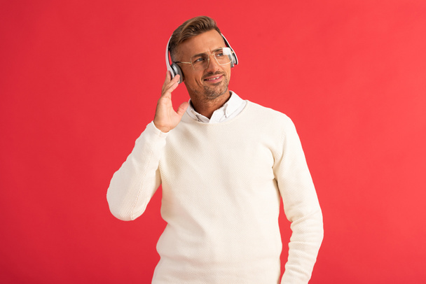 hombre feliz escuchando música en auriculares aislados en rojo
  - Foto, Imagen