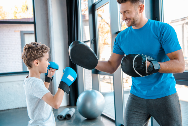 happy father and cute son boxing in gym  - 写真・画像