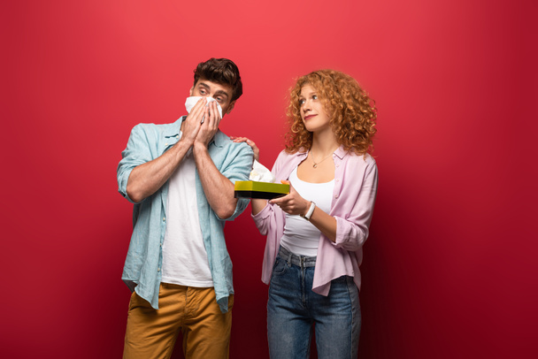 woman and diseased man with runny nose holding paper napkins, on red - Photo, Image