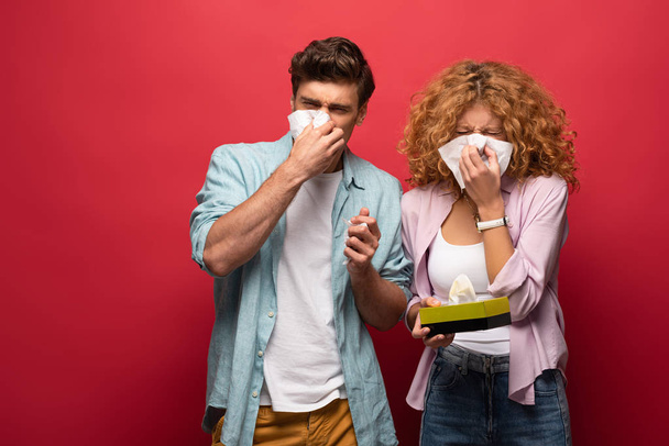 sad diseased couple with runny nose holding paper napkins, on red - Foto, Imagem