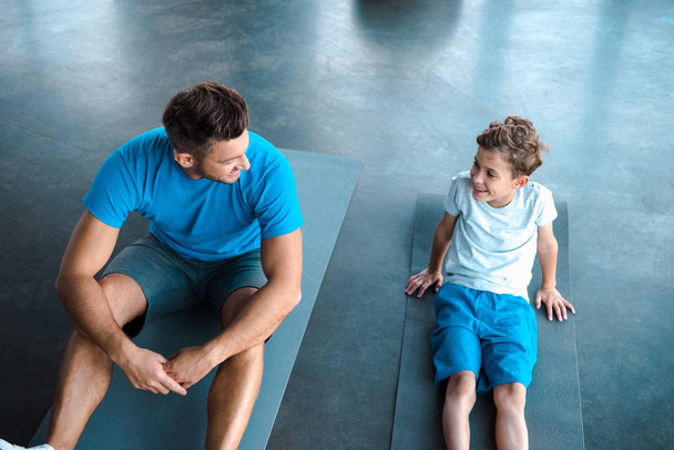 overhead view of cute kid and father looking at each other in gym  - 写真・画像