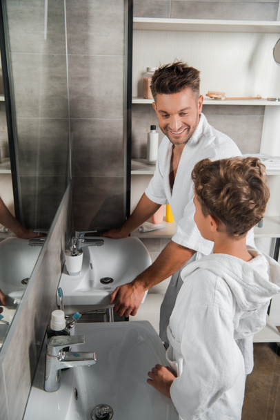 szelektív fókusz boldog apa nézi fia közelében fürdőszoba mosogatók  - Fotó, kép