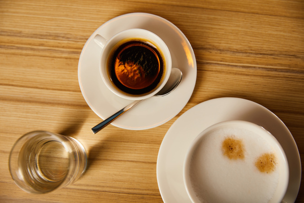vue de dessus des tasses avec café près du verre d'eau dans le café
  - Photo, image