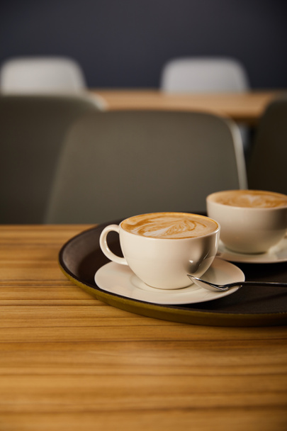 selective focus of cappuccino in white cups on black tray  - Foto, Bild