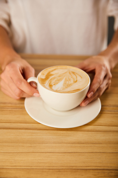 cropped view of woman holding cup with cappuccino  - Φωτογραφία, εικόνα