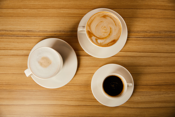 top view of saucers with white cups of tasty coffee in cafe  - Foto, immagini