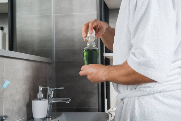 cropped view of man holding green bottle with mouthwash  - Valokuva, kuva