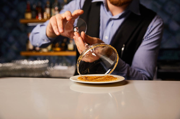vista recortada de barman sosteniendo vaso de margarita cerca platillo con azúcar morena
  - Foto, imagen
