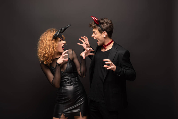 scary couple posing in traditional halloween costumes on black - Φωτογραφία, εικόνα