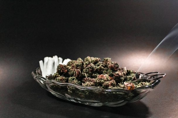 Elegante plato de cristal con capullo de marihuana, tijeras y una docena de porros
 - Foto, imagen