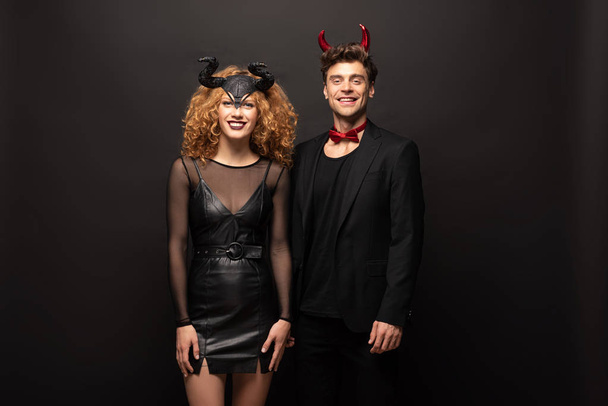 hermosa sonriente pareja posando en halloween trajes en negro
 - Foto, Imagen