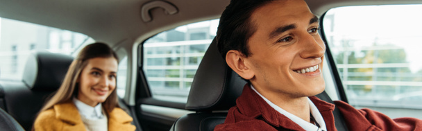 Concentration sélective du chauffeur de taxi souriant et de la femme sur le siège arrière de la voiture, prise de vue panoramique
 - Photo, image