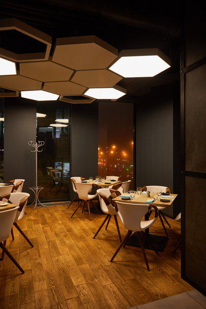 glazen en borden op houten tafels in modern restaurant  - Foto, afbeelding