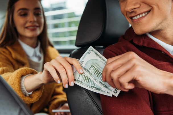 タクシー運転手にドル紙幣を与える乗客の選択的焦点 - 写真・画像