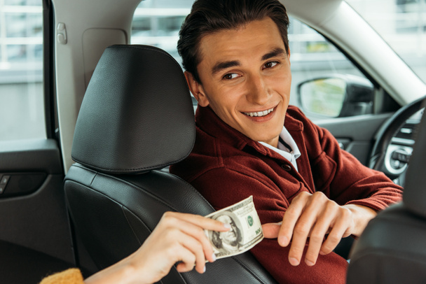 Glimlachende taxichauffeur neemt contant geld van vrouw hand - Foto, afbeelding