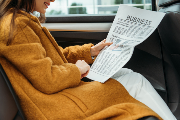 Vista recortada de la mujer leyendo el periódico en el asiento trasero del taxi
 - Foto, Imagen