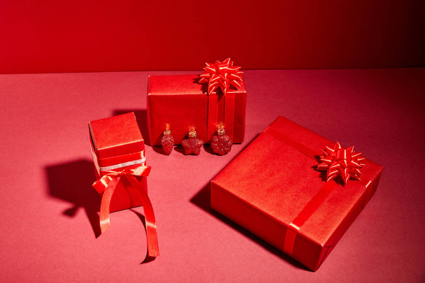 red wrapped festive gift boxes with ribbons and bows on red background - Photo, Image
