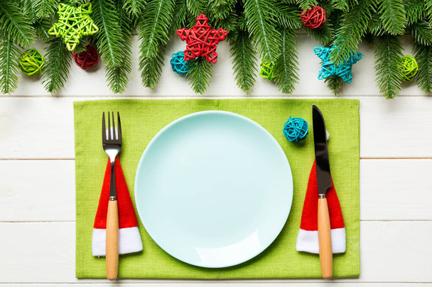Вид зверху на виделку, ніж і тарілку, оточену ялинкою та різдвяними декораціями на дерев'яному тлі. Новорічна ніч і святкова вечеря концепція
 - Фото, зображення