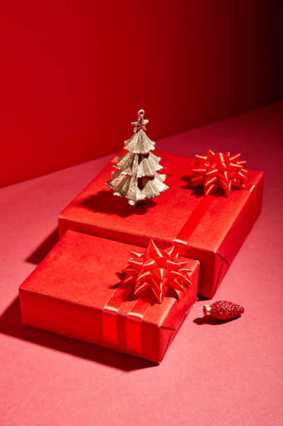 red gift boxes and decorative golden Christmas tree on red background - Foto, Imagen