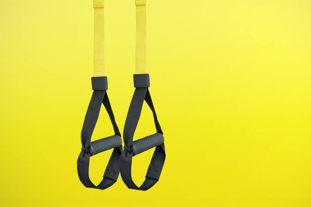 Straps training loop equipment. Black loop functional training equipment on yellow background. Sport accessories. Fitness and Gym workout items for Healthy. - Φωτογραφία, εικόνα