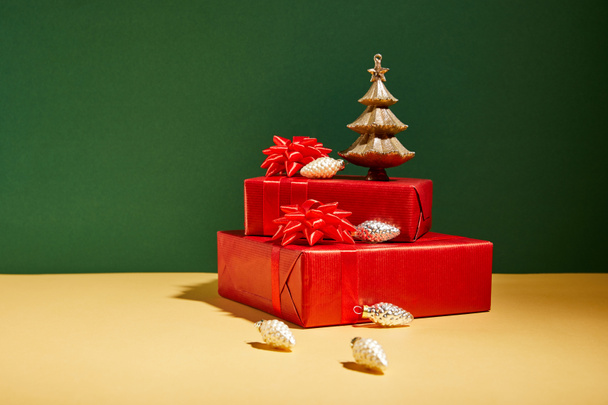 red gift boxes and golden Christmas decor on yellow and green background - Photo, Image