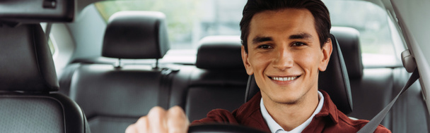 Panoramische opname van een glimlachende man rijdende auto - Foto, afbeelding