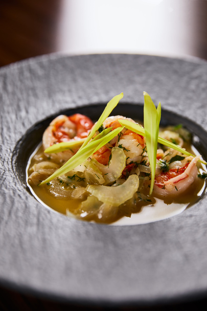 close up view of delicious restaurant soup with shrimps in black plate - Foto, afbeelding