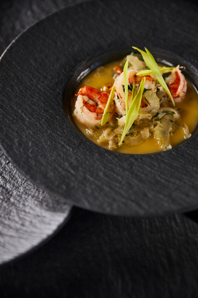delicious restaurant soup with shrimps in black plate - Foto, afbeelding
