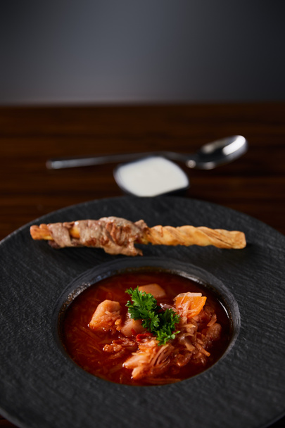 traditional ukrainian borscht garnished with parsley in black plate - Photo, image