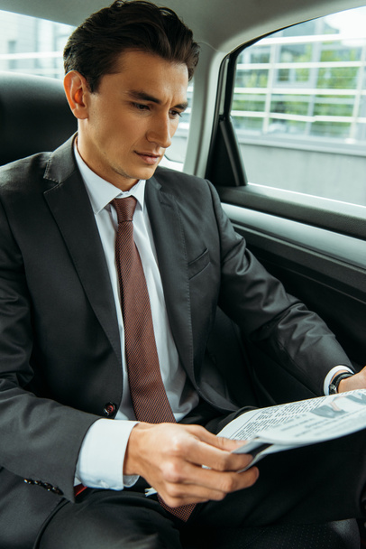 Handsome businessman reading newspaper in taxi - Foto, afbeelding