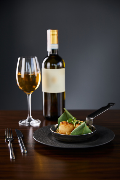 delicious grilled scallops served with cutlery and white wine on wooden table - Foto, afbeelding