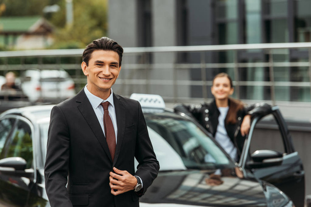Selective focus of smiling businessman and taxi driver by car - Photo, Image