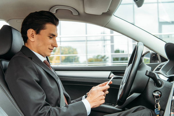 ドローン車の中でスマートフォンを使うビジネスマンの側面図 - 写真・画像