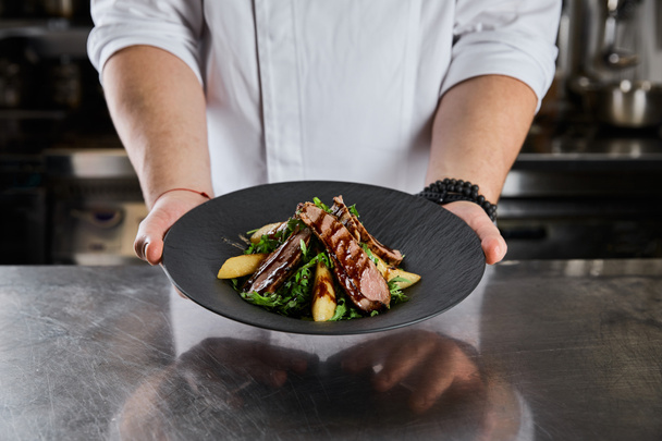 vista parcial del plato de la celebración del chef con rúcula, carne y papa en la cocina en el restaurante
 - Foto, imagen