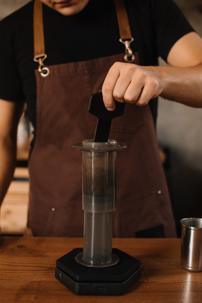 обрезанный вид на бариста, готовящего кофе с аэропрессом
 - Фото, изображение