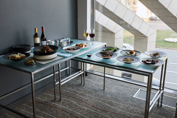 bebidas y platos servidos en mesas de vidrio en el restaurante para la comida stand-up
 - Foto, Imagen