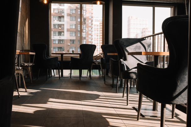balcón con mesas y sillas en la moderna cafetería loft a la luz del sol
 - Foto, imagen