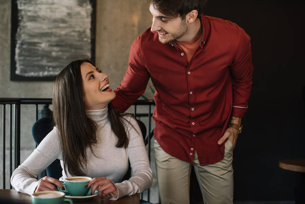 smiling young couple looking at each other on balcony in coffee shop - Photo, Image