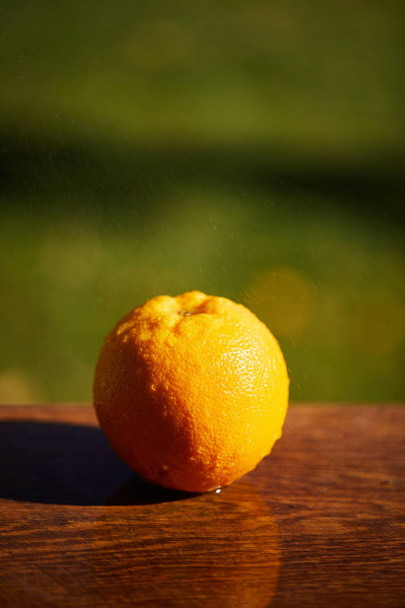 enfoque selectivo de naranja entero y húmedo en la superficie de madera
  - Foto, Imagen