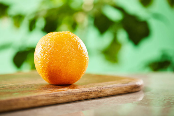 selective focus of whole orange on wooden cutting board - Foto, Bild
