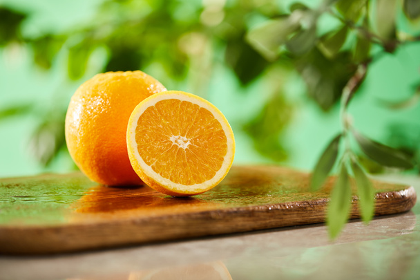 selective focus of cut and whole oranges on wooden cutting board - Photo, Image