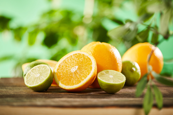 selective focus of cut, whole oranges and limes on wooden surface  - Fotó, kép