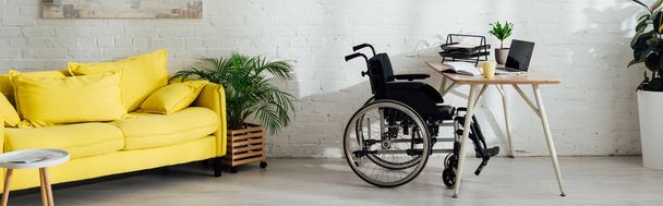 Інтер'єр вітальні з робочим місцем та інвалідним кріслом за столом, панорамний знімок
 - Фото, зображення