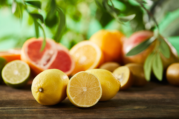 selective focus of cut and whole lemons on wooden surface  - 写真・画像