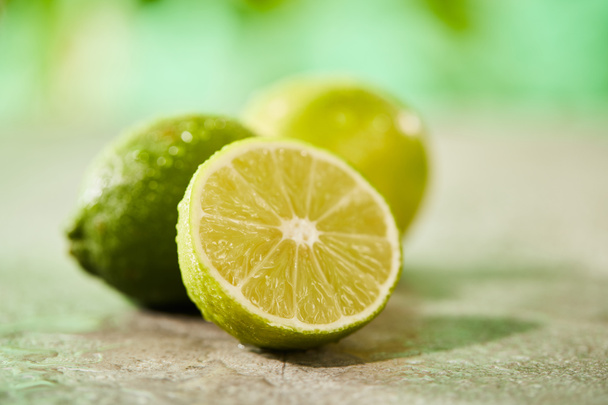 selective focus of whole and cut limes with drops on marble surface  - 写真・画像