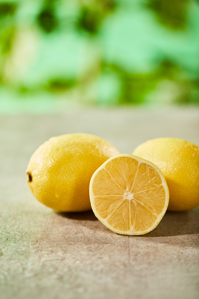 selective focus of whole and cut lemons with drops on marble surface  - Photo, Image