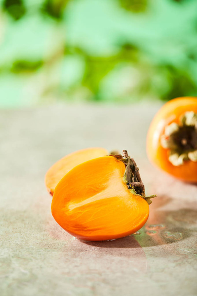 selective focus of whole and cut persimmons on marble surface  - Fotó, kép