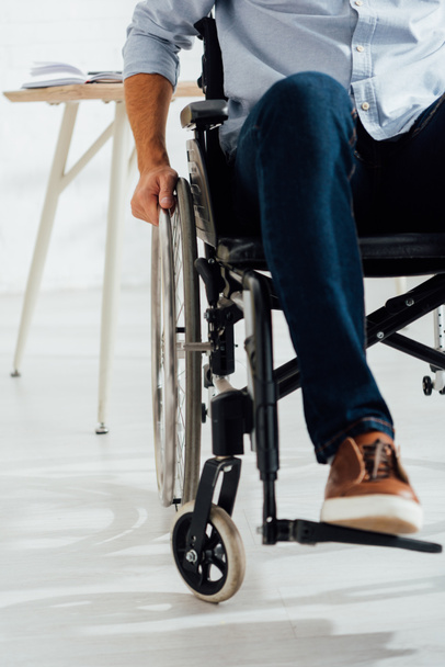 Cropped view of man holding hand on wheelchair wheel - Photo, Image