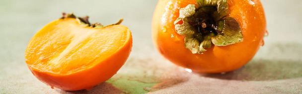 panoramic shot of whole and cut persimmons on marble surface  - Fotoğraf, Görsel