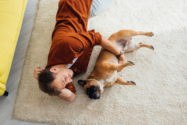 Vista aérea del hombre con bulldog francés acostado en la alfombra
 - Foto, Imagen